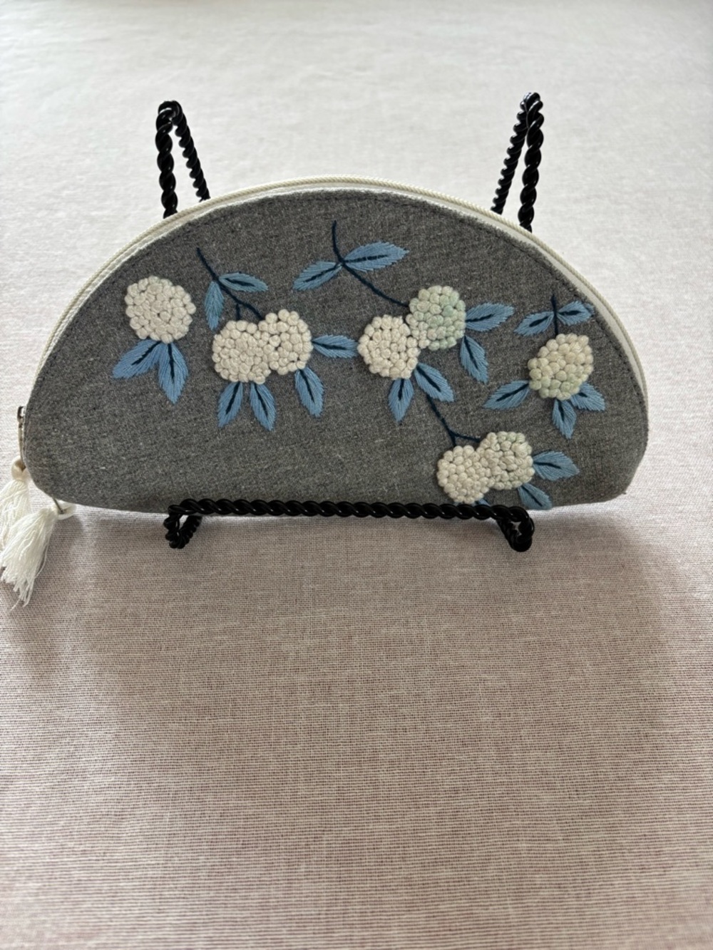 Grey embroidered floral half moon clutch.